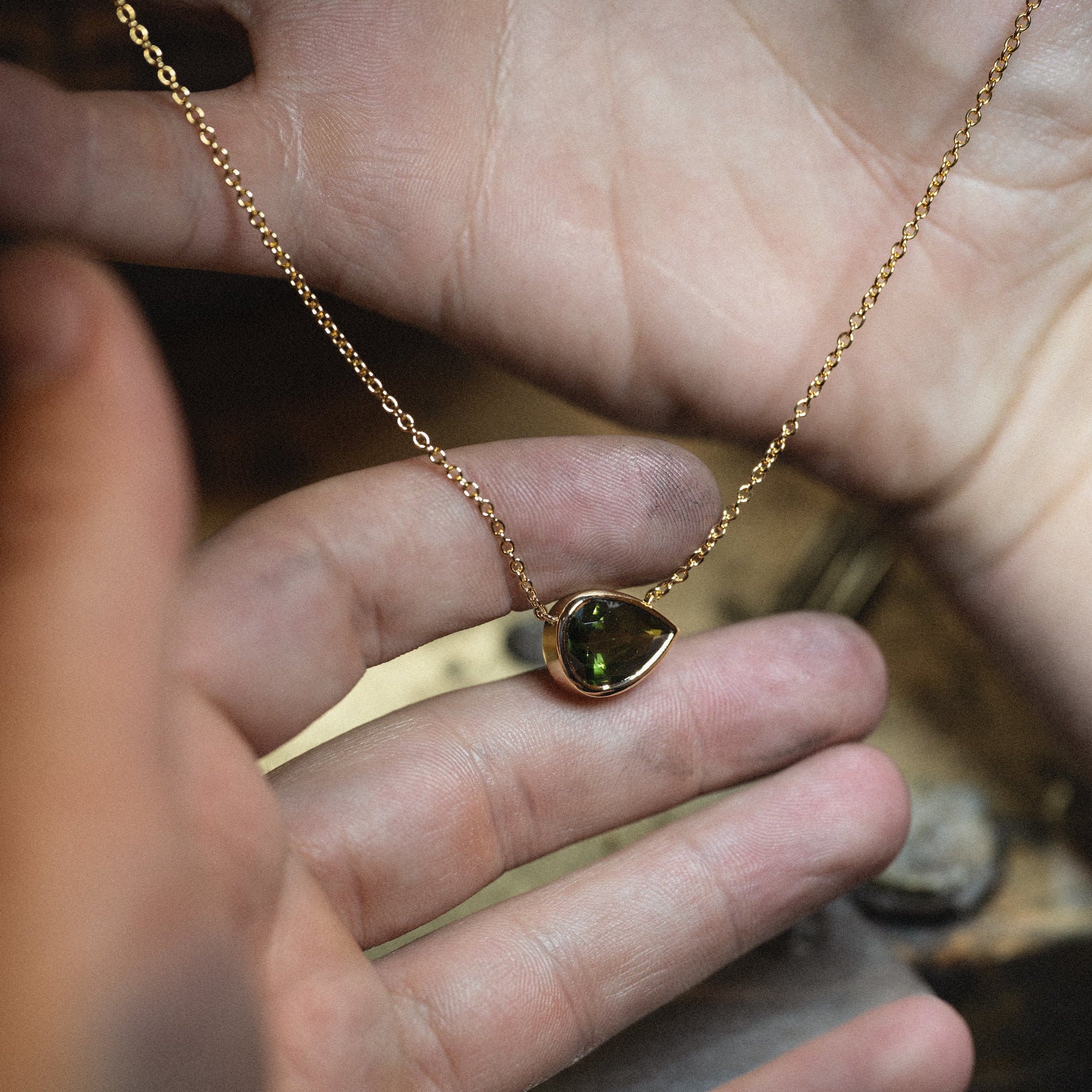 Micheli pear-shaped gemstone necklace held between fingers