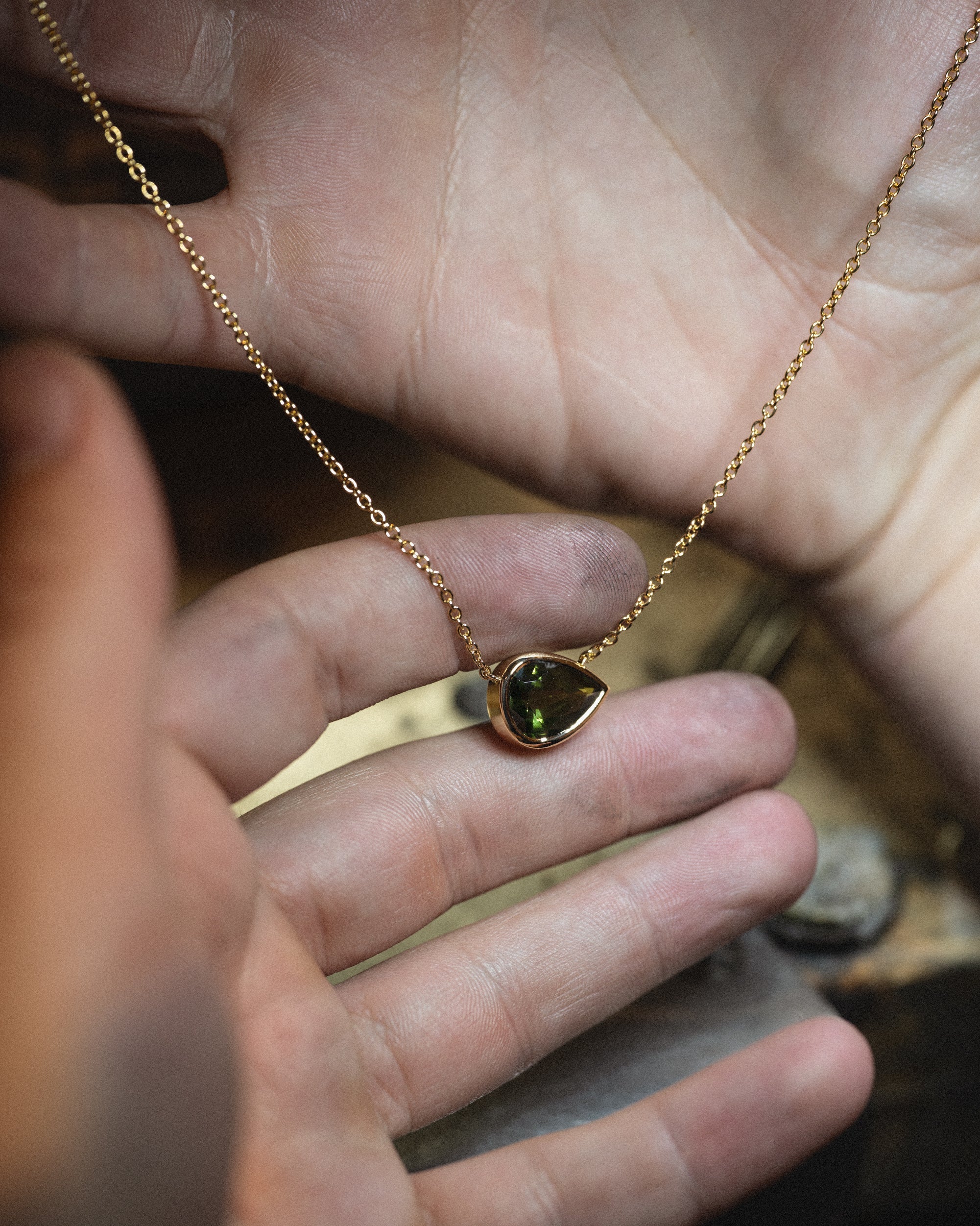 Micheli pear-shaped gemstone necklace held between fingers